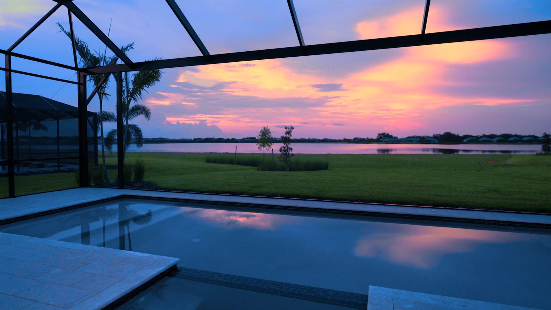 Sunset over the lake from a screened lanai and pool at a Waterside model residence, Lakewood Ranch